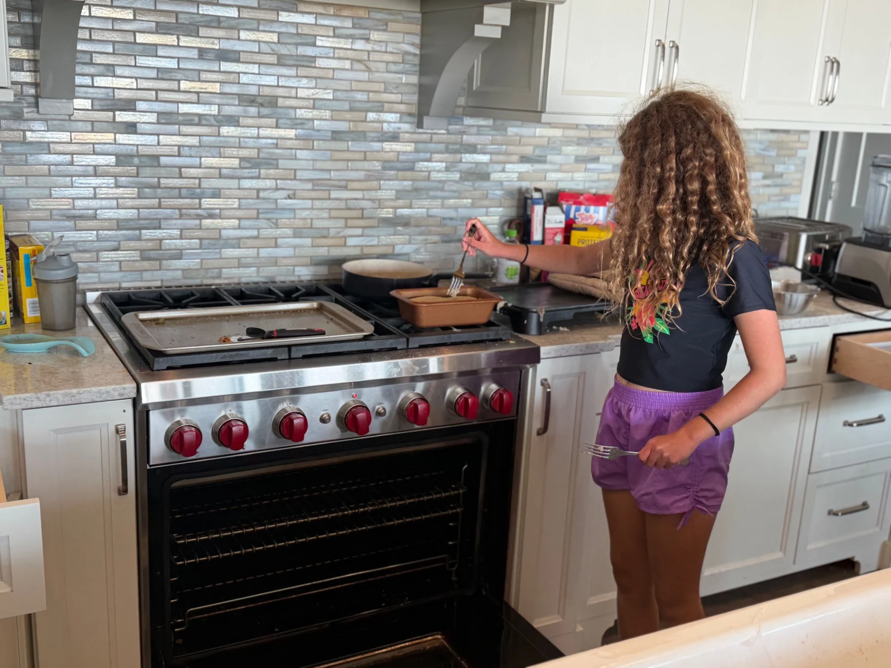 Our young baker checking a fresh pan of treats on the stove in our home kitchen